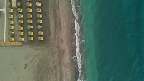 Océano-De-Color-Puro-Y-Tumbonas-En-La-Playa-De-Arena,-Vista-De-Arriba-Hacia-Abajo