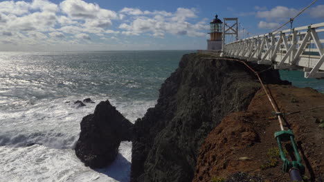 famous point bonita lighthouse in marin county with waves crashing up against the cliff face