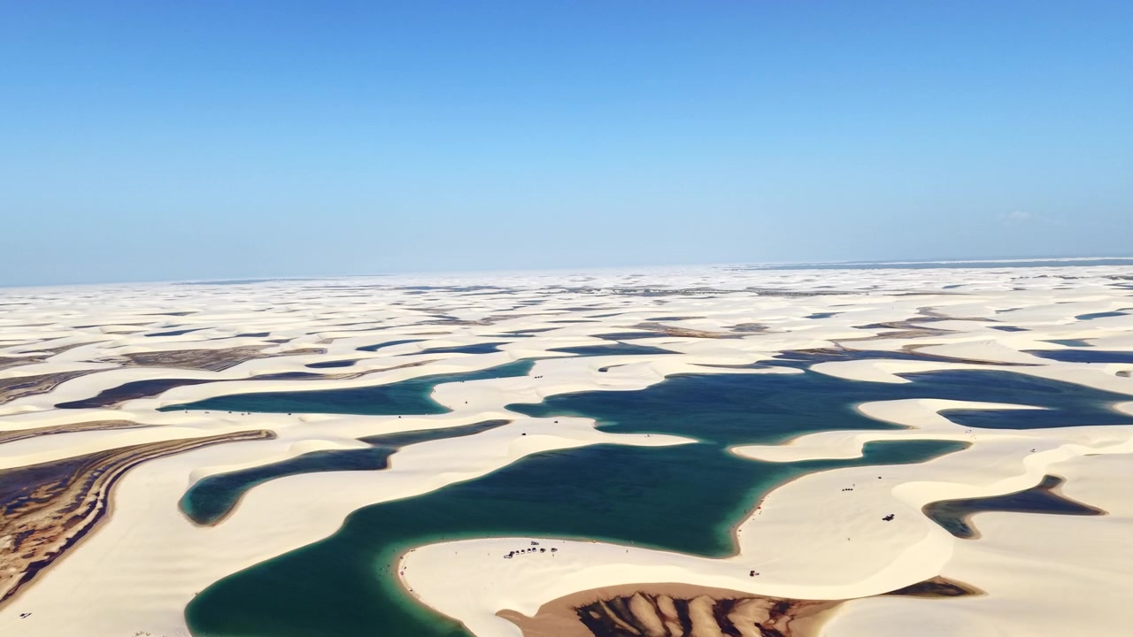 Dronebillede af buede hvide klitter og blågrønne laguner i ørkenen, Lencois Maranhenses, Brasilien