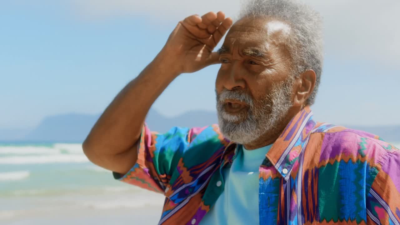 Tampilan depan seorang pria lansia Afrika-Amerika yang aktif dengan tangan di dagu dan tangan di belakang kepala di pantai 4k