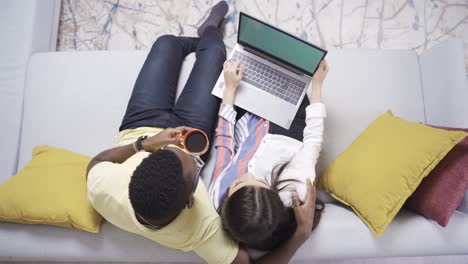 una pareja multiétnica trabajando con una computadora portátil en su oficina en casa.