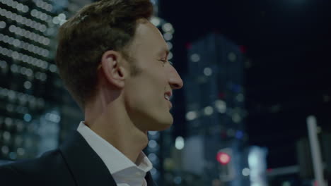 Portrait-of-a-young-business-man-smiling-at-night-among-skyscrapers