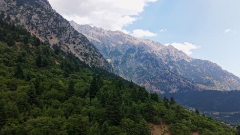 drone tracks along lush green mountain range with misty backdrop in central greece region