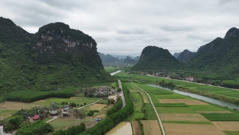 tomada aérea de un avión no tripulado de un río que pasa por colinas llenas de vegetación y pequeñas casas