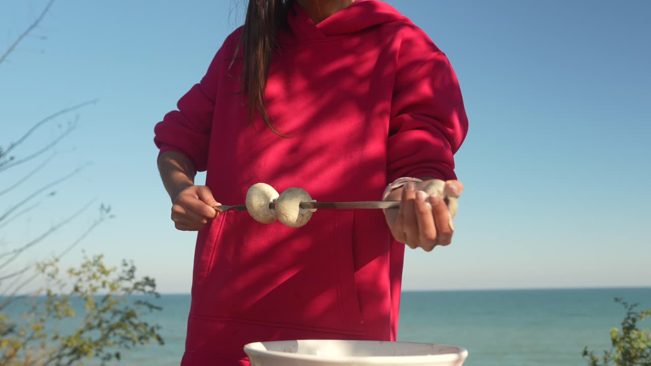 해변에서 지이에 버섯을 요리하는 소녀