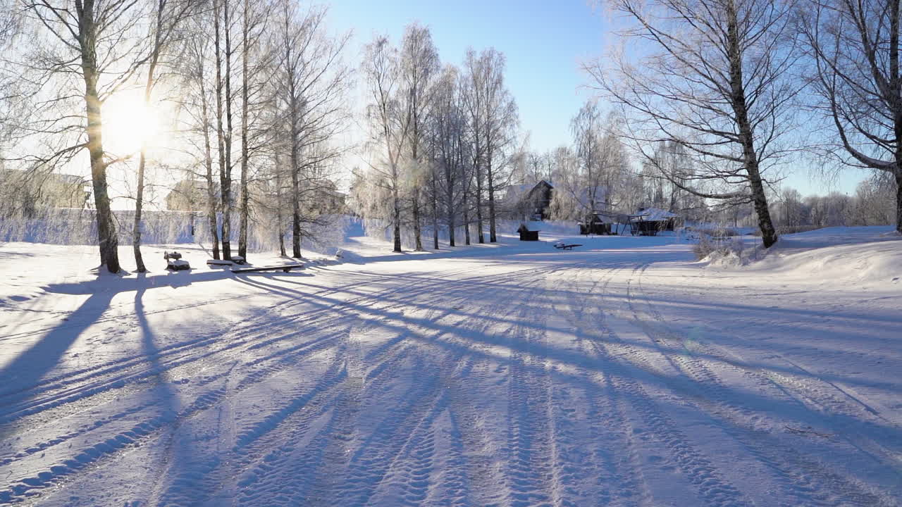 눈 속에 타이어 자국이 있는 시골의 화창한 겨울 아침에 느린 폭설
