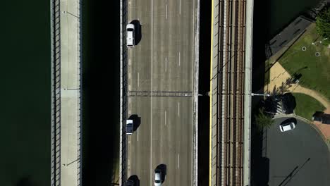 top down drone view of two modern day electric trams passing on a busy vehicle and pedestrian bikeway bridge. gold coast queensland australia