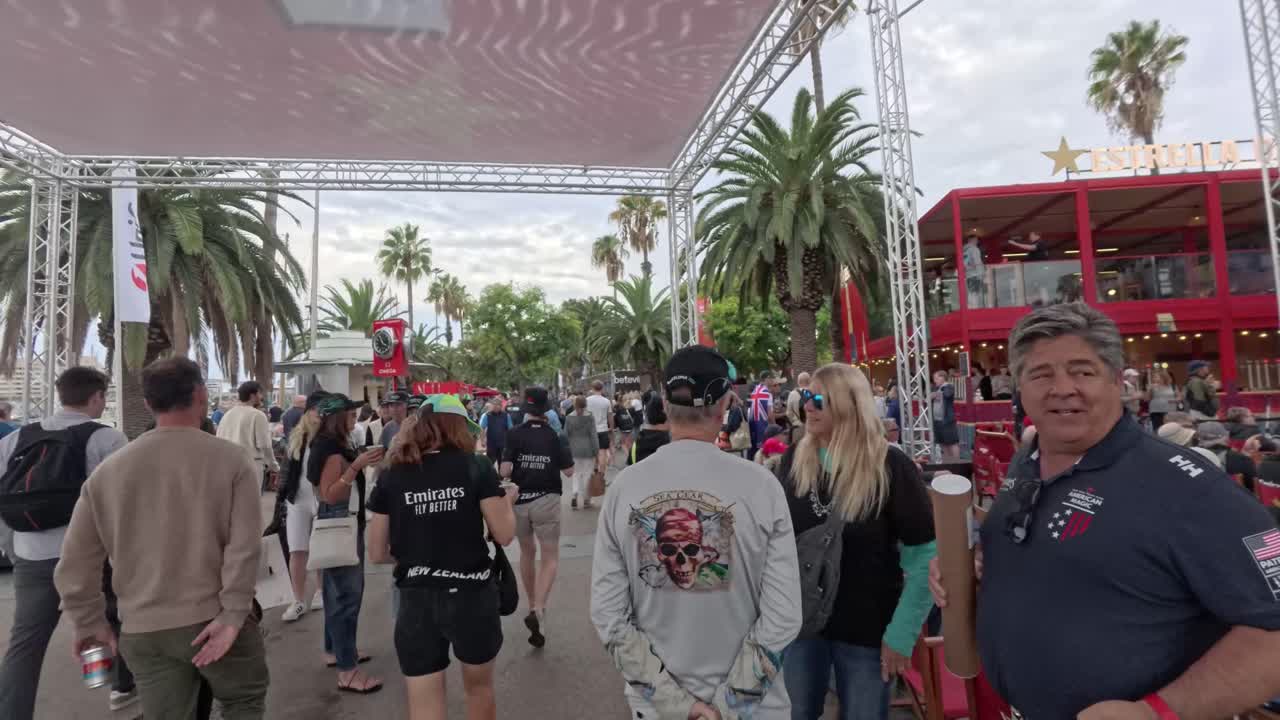 Crowd outside watching the 37th America´s cup on a giant screen. Drinks, men, women