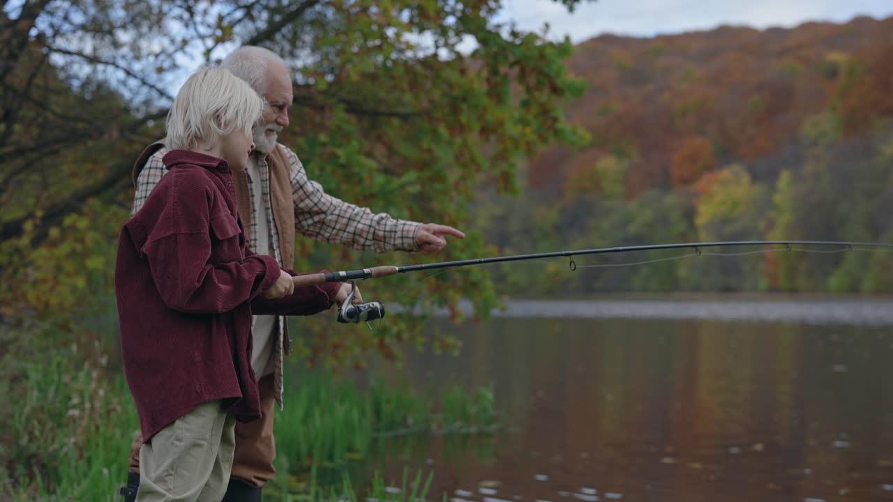 Grandfather and grandson fishing by a lake in autumn