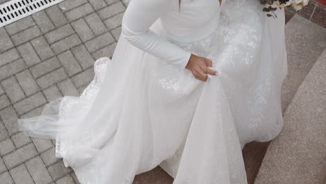 Young-bride-wearing-long-white-wedding-dress-goes-up-stairs