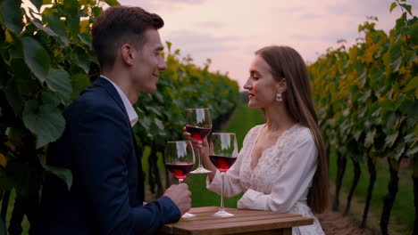 romantic couple enjoying wine in a vineyard at sunset