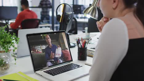 Caucasian-businesswoman-sitting-at-desk-using-laptop-having-video-call-with-male-colleague