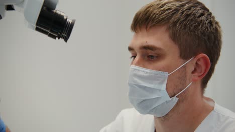 médico examinando al paciente con el microscopio