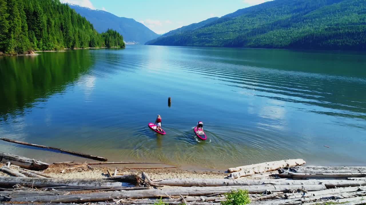 Aerial of couple on stand up paddle board oaring in river 4k