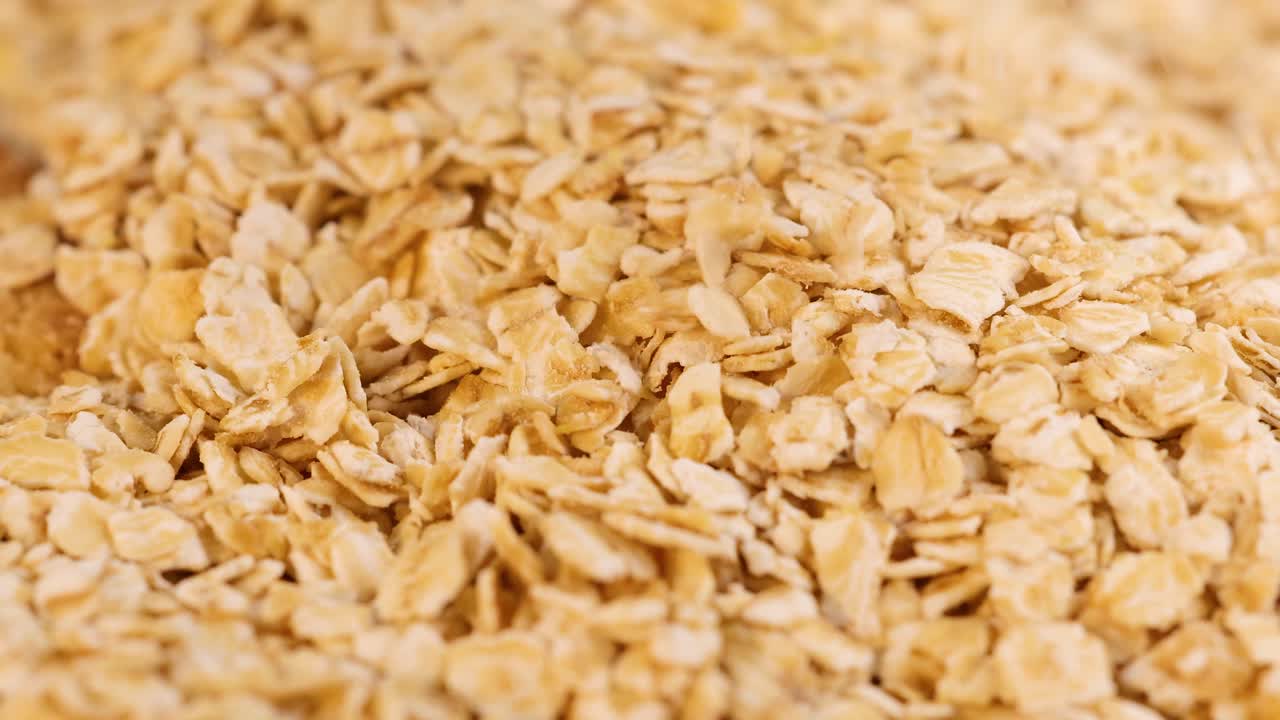 A detailed examination of rolled oats cascading in a warm, natural light setting, highlighting texture and movement