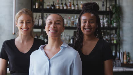 portrait of female owner of restaurant bar with team of female waiting staff standing by counter