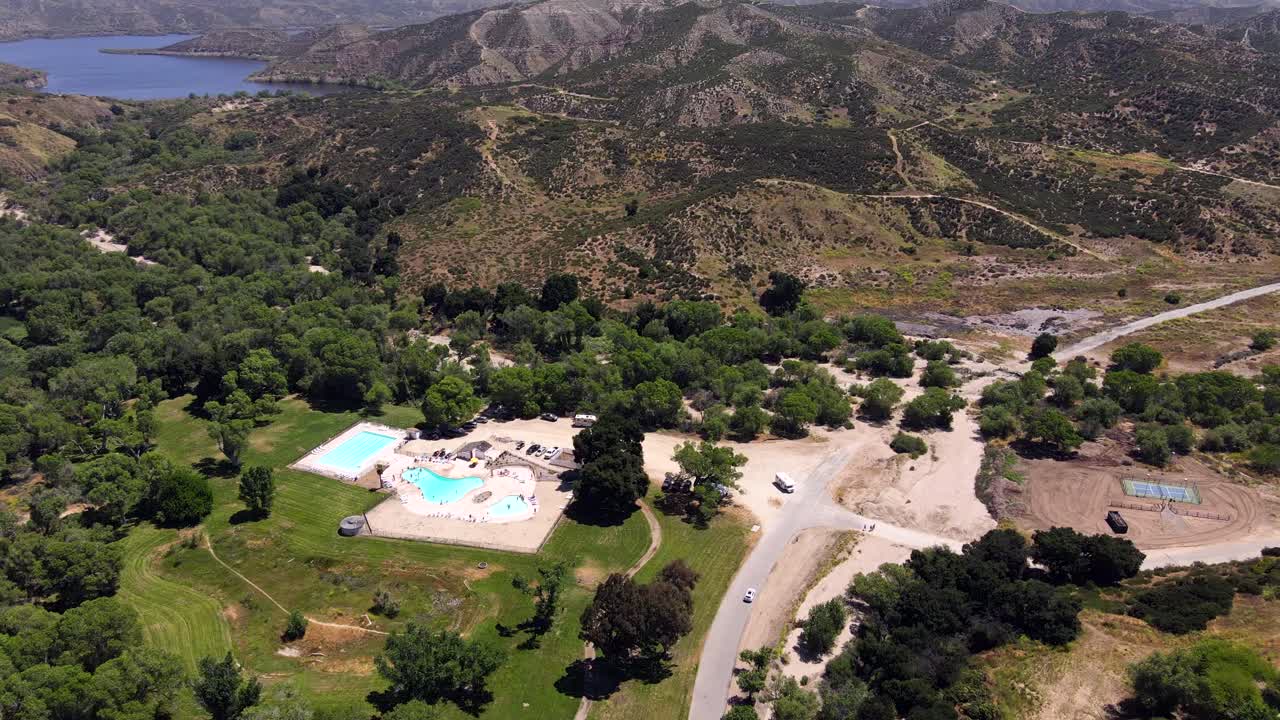 Aerial View of a Campground with Swimming Pool near a Lake and Mountains