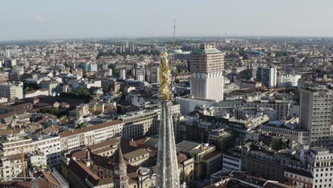 milan golden symbol on top of cathedral rooftop, aerial orbit view