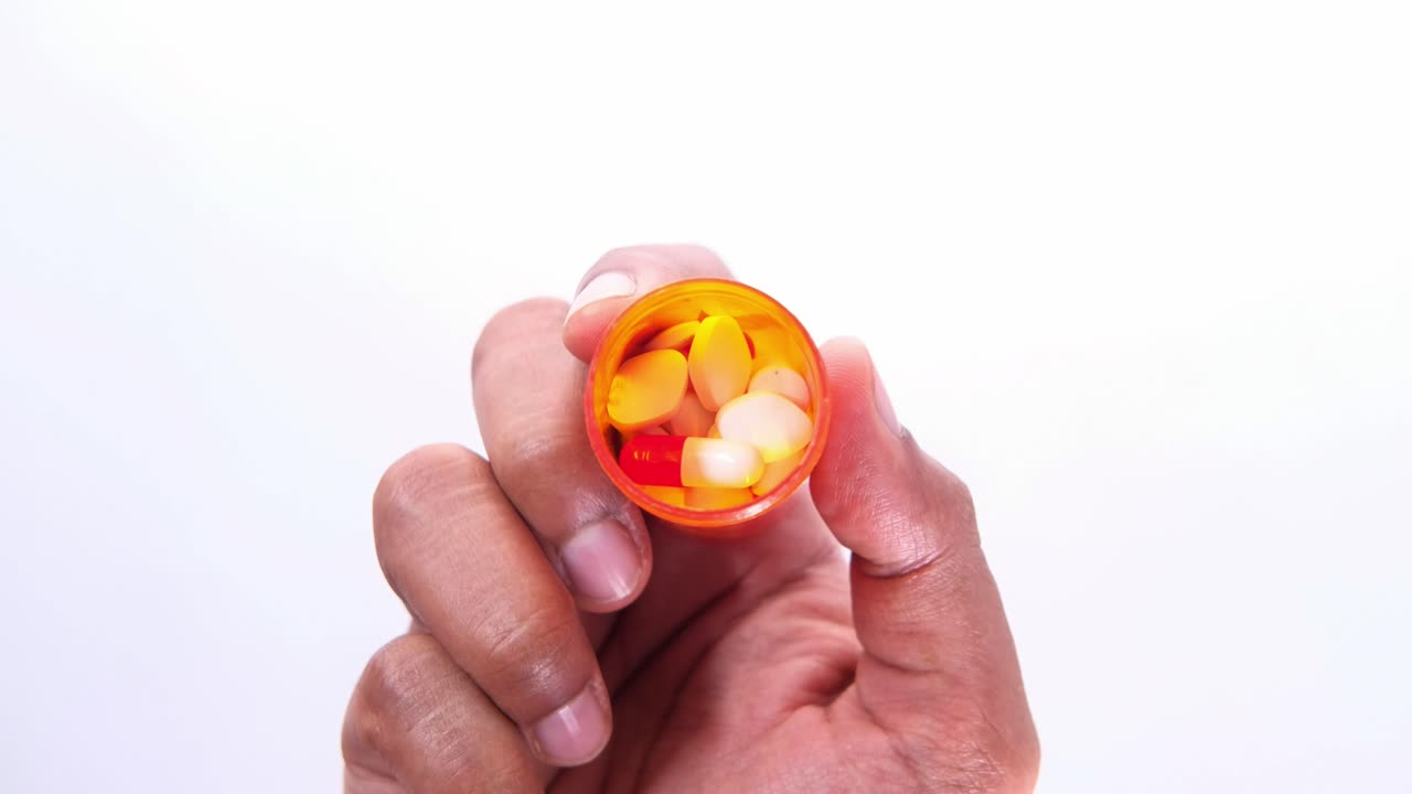 mano sosteniendo un frasco de pastillas con medicina