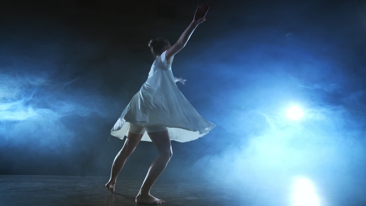 Woman in white dress on stage with smoke dancing modern ballet