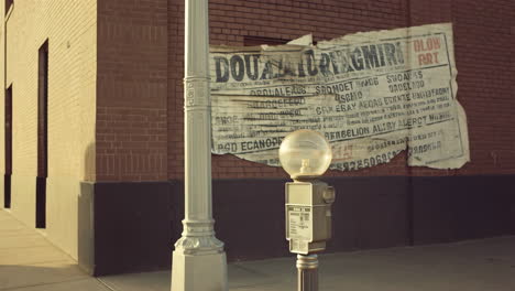 urban street scene with brick building, parking meter, and tattered poster