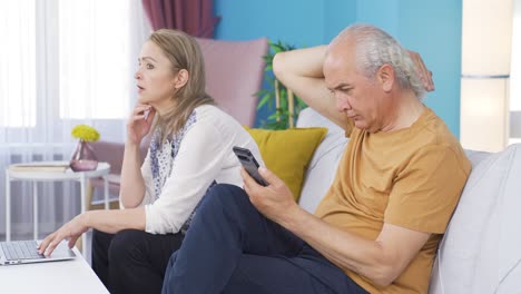 pareja casada pasando el rato en la computadora portátil y el teléfono. uso de la tecnología en casa.