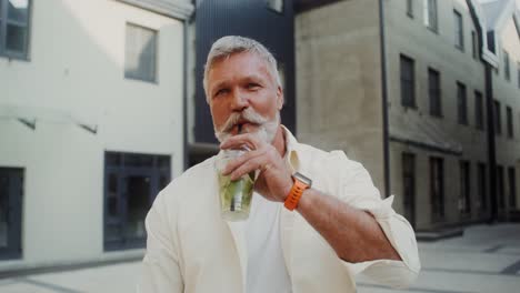 older man enjoying a drink outdoors