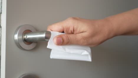 cleaning a door handle with a tissue