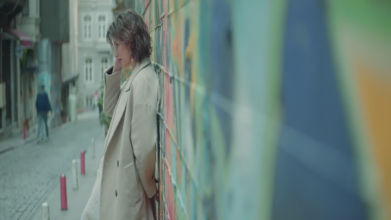 다채로운 도시 거리에서 베이지색 코트를 입은 여자