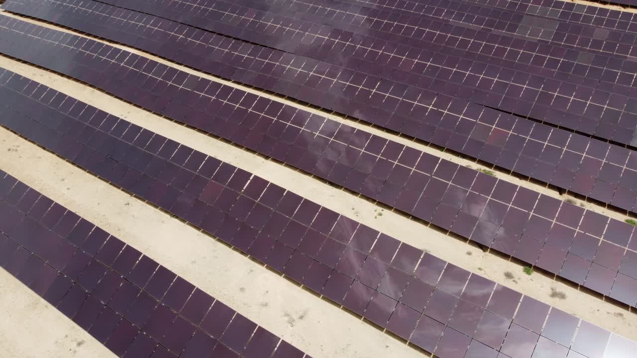 Aerial view from a drone turning over a solar power station with clouds reflection in the solar panels in Spain