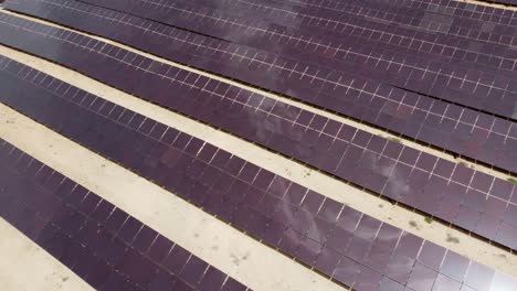 aerial view from a drone turning over a solar power station with clouds reflection in the solar panels in spain