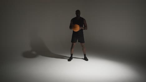 studio action shot of male basketball player dribbling ball against white background 2