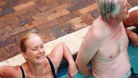 ancianos relajándose mientras interactúan cerca de la piscina