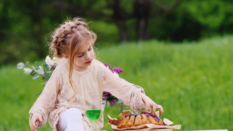 Niña-Feliz-Con-Un-Vestido-Ligero-Elegante-Con-Un-Peinado-Desaliñado-Se-Sienta-En-Una-Mesa-Decorada-Y-Come-Un