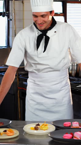 chef sonriente apoyado en el mostrador de postres