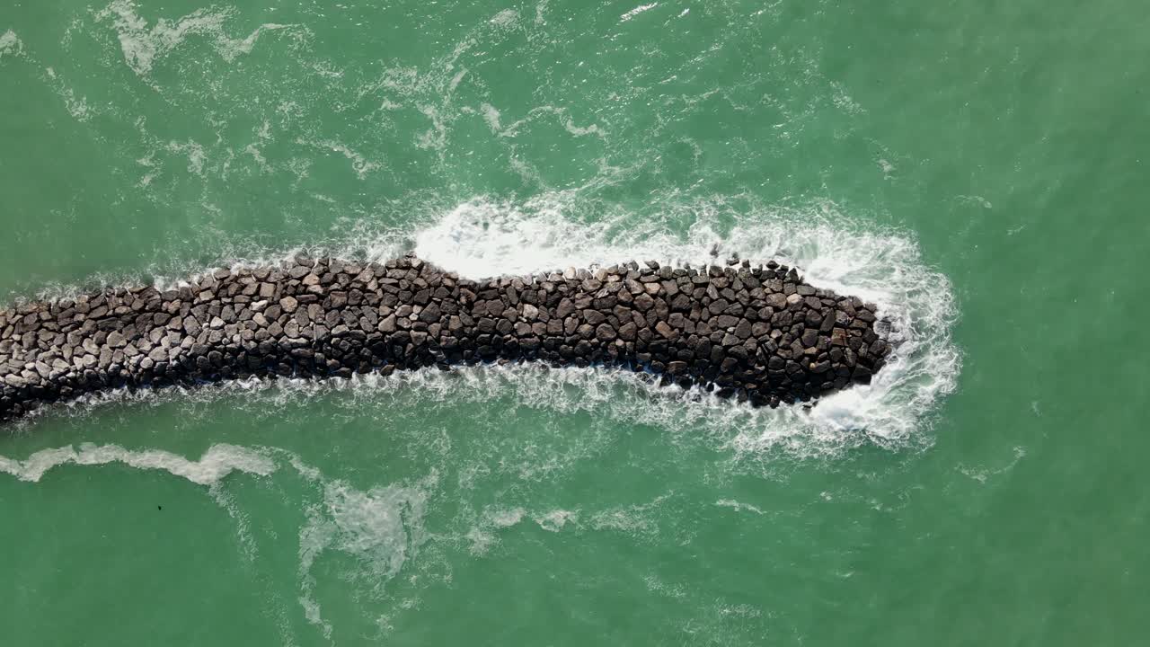 4k:거친 바다의 드론 보기, 맨돌에 부딪치는 파도, 부서지는 파도와 바위에 거품이 있는 깊고 푸른 바다