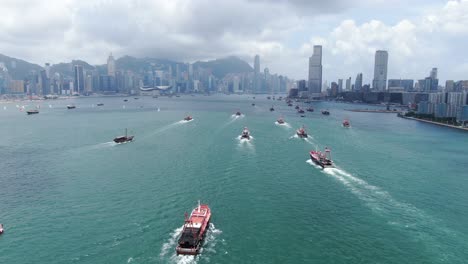 convoy de barcos de pesca locales que causan en la bahía victoria de hong kong, con el horizonte de la ciudad en el horizonte, vista aérea