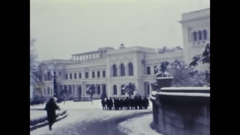 group of people standing in front of a soviet building. circa ussr 1970: a snapshot of soviet people standing together in front of a historic building in the ussr.