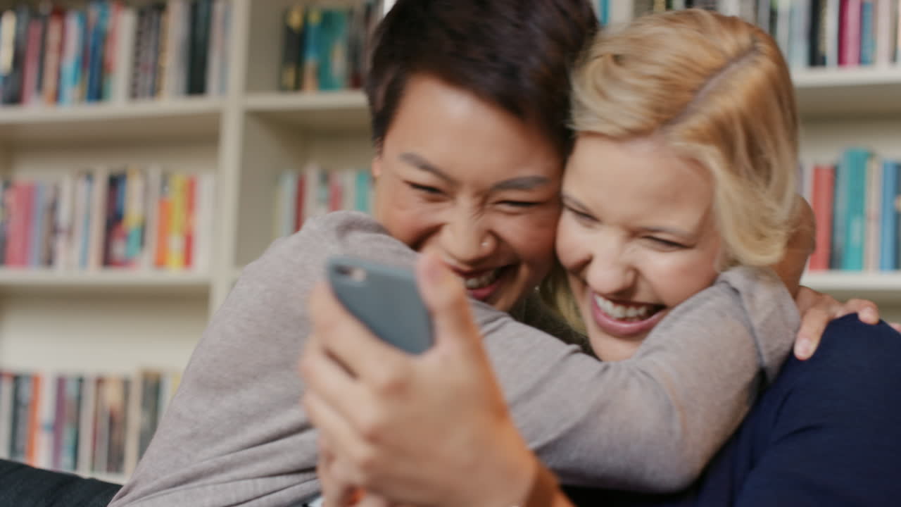 집 에서 친구 들 이 스마트 폰 을 이용 하여 웃고 즐기고 있다