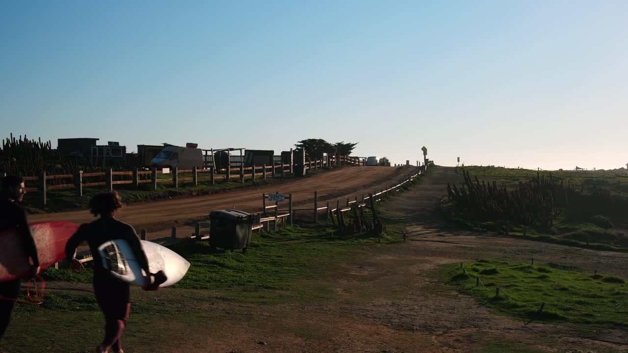 surfers with surfboards walking runing towards the surf point gaze through the native cactus and with the light of a beautiful sunset in pichilemu punta de lobos chile colchagua doing outdoor sports