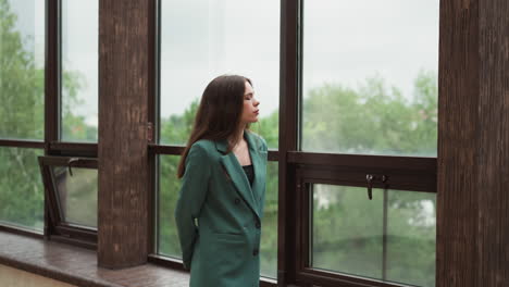 woman leader strolls along expansive windows. lady brows furrowed in contemplation over dwindling client contracts. financial uncertainty about future