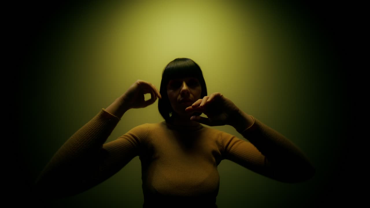 mujer posando en una camiseta amarilla con una iluminación dramática