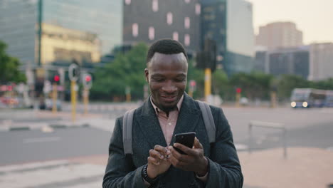 portrait of handsome young african american man texting browsing using smartphone mobile app on busy city street