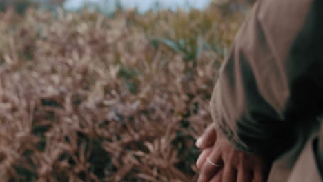 mujer joven solitaria parada en el campo frotándose las manos frías sintiéndose deprimida en un día nublado de invierno