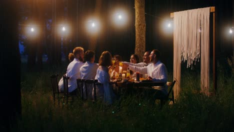 amigos disfrutando de una cena en el bosque por la noche