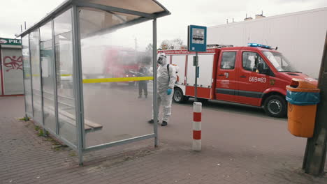 cleaners in protective suits disinfecting bus stop in warsaw. prevention of the coronavirus spread