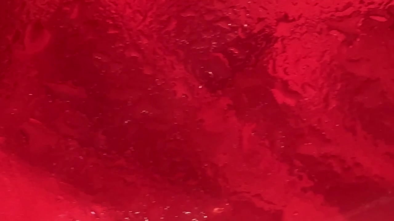 Goccioline d'acqua che scorrono su una superficie rossa vibrante