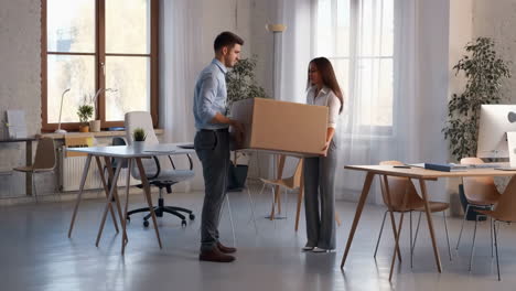 two office workers collaboratively carrying a large cardboard box