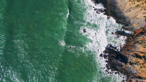 aerial view stony coastline washing by stormy ocean. sea waves splashing cliffs.