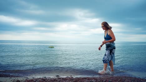 Mujer-Mayor-Caminando-En-La-Playa-En-Karkle,-Lituania---Amplia,-Cámara-Lenta